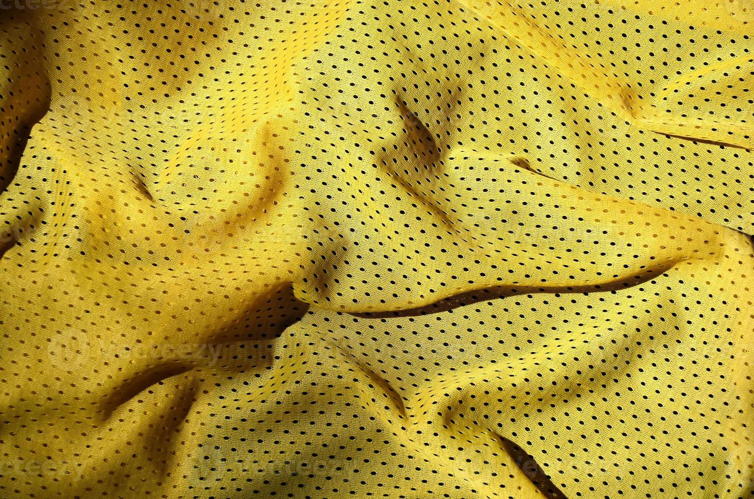 Sport clothing fabric texture background. Top view of yellow polyester nylon cloth textile surface. Colored basketball shirt with free space for text photo