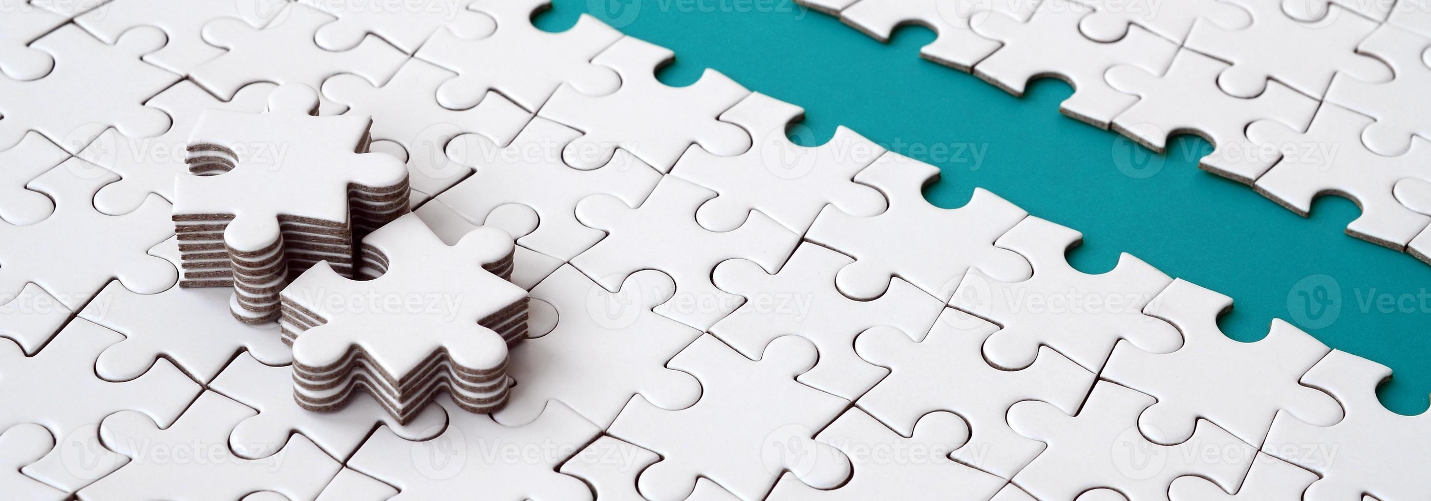 The blue path is laid on the platform of a white folded jigsaw puzzle. The missing elements of the puzzle are stacked nearby. Texture image with space for text photo