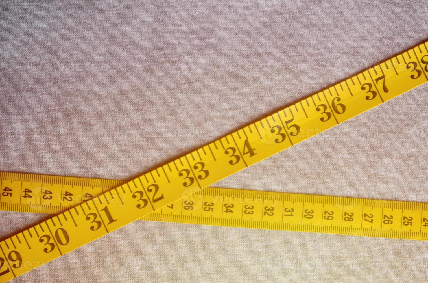 Yellow measuring tape lies on a gray knitted fabric photo