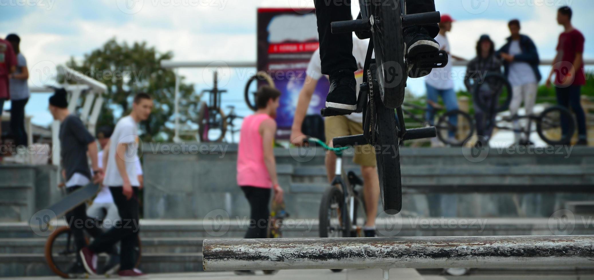 un ciclista salta sobre una tubería en una bicicleta bmx. mucha gente con bicicletas en el fondo. concepto de deportes extremos foto