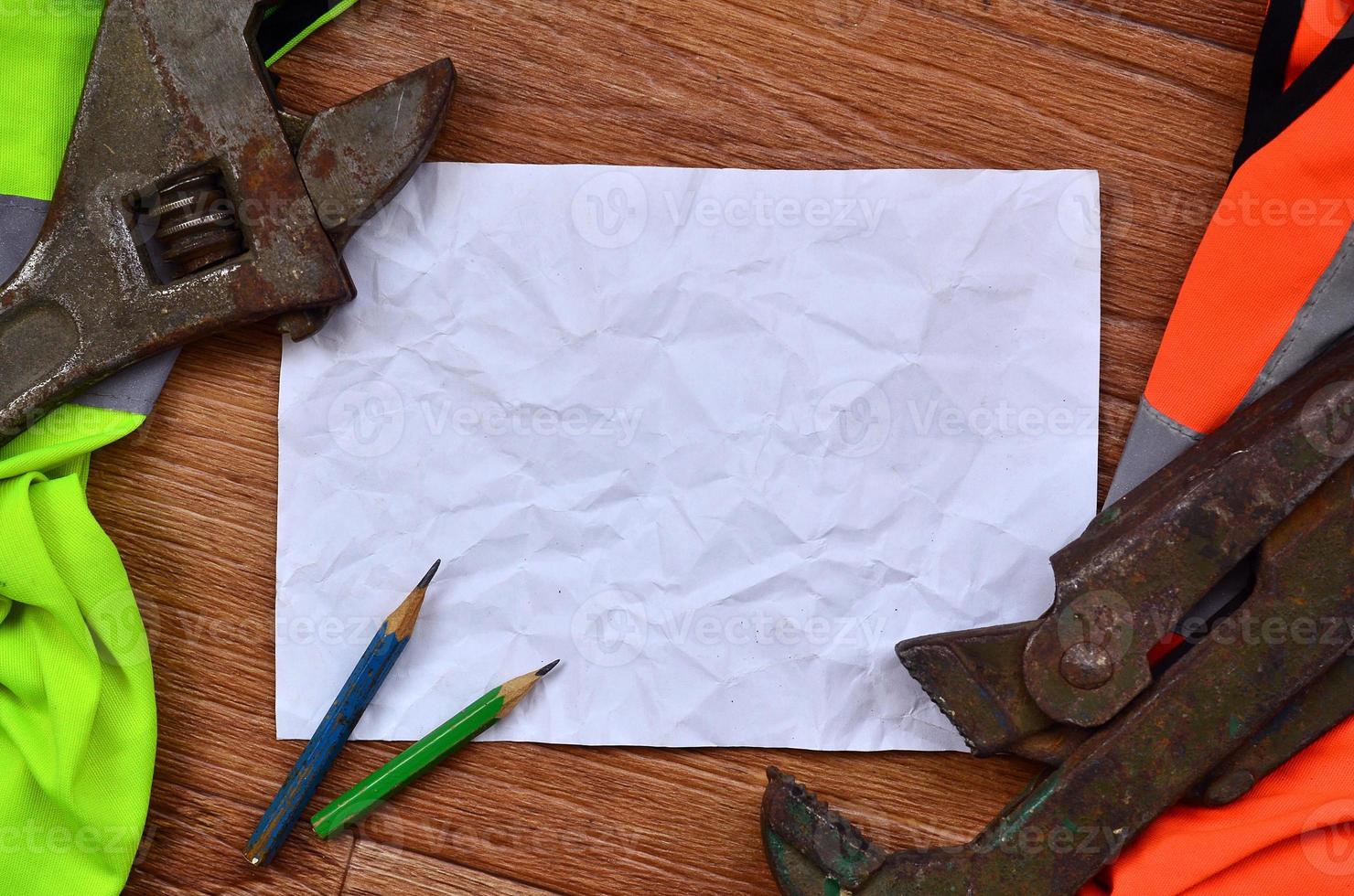 A crumpled sheet of paper with two pencils surrounded by green a photo