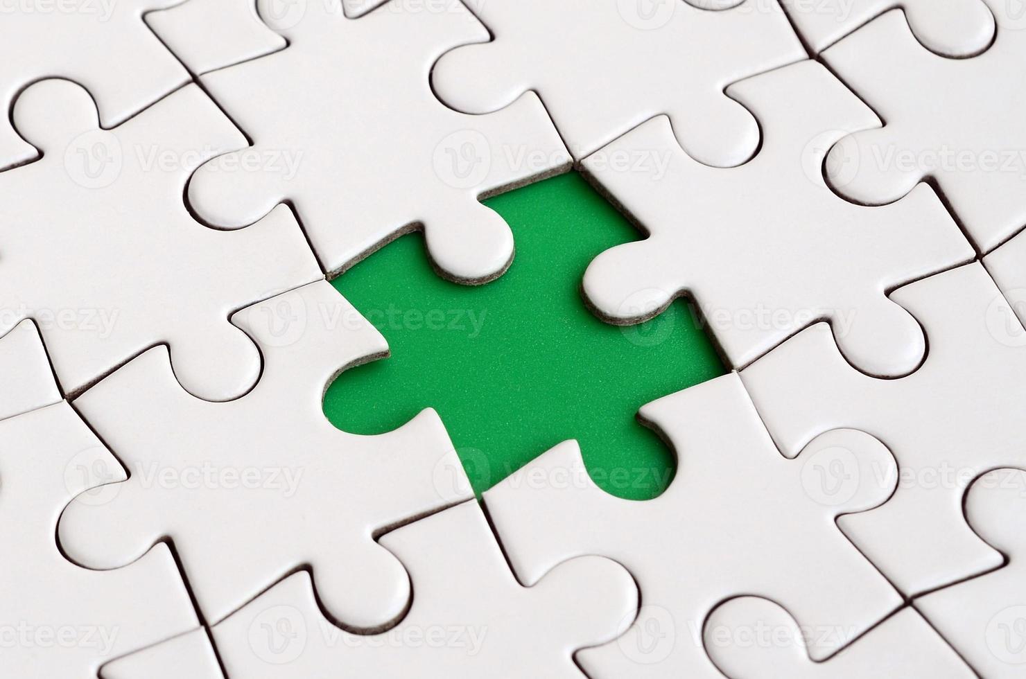 Close-up texture of a white jigsaw puzzle in assembled state with missing elements forming a green pad for text. Copy space photo