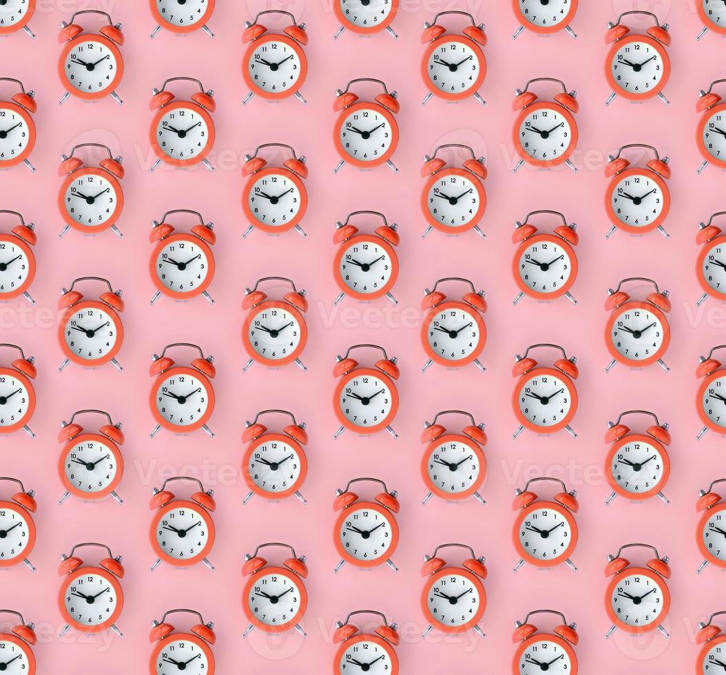 Wasting time concept. Many coral red alarm clock photo