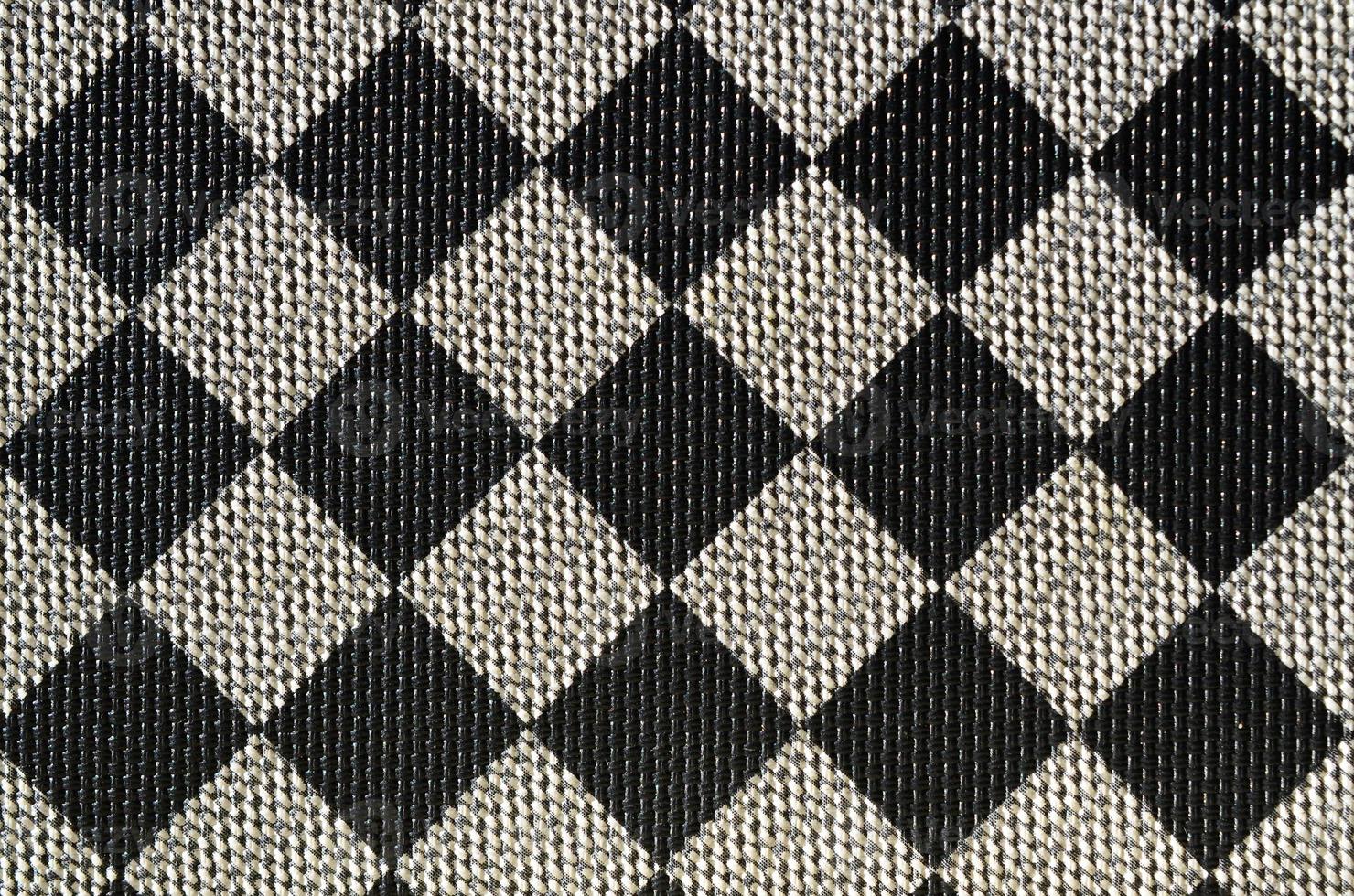 Plastic texture in the form of a very small cloth binding, painted in black and gray in the style of a chessboard. Macro shot photo