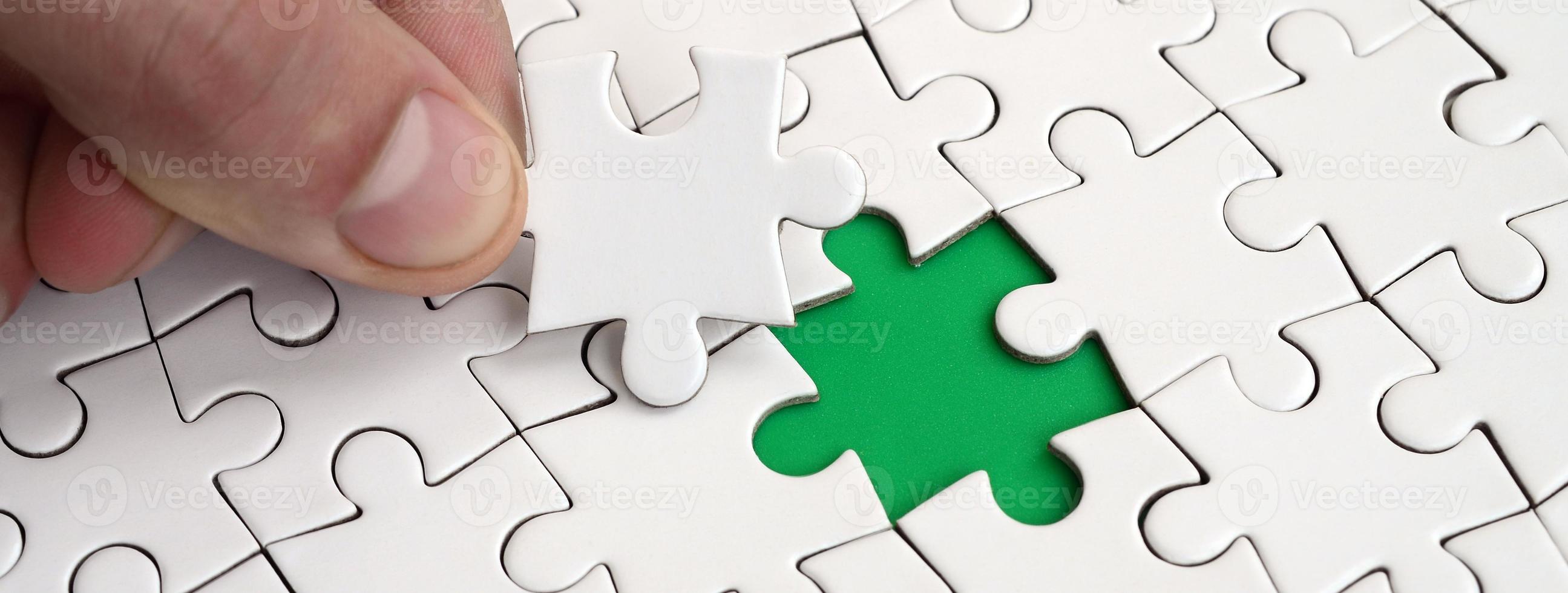 The human hand fills the last missing elements of the surface from the jigsaw puzzle. The concept of the completion of the initiated cases photo