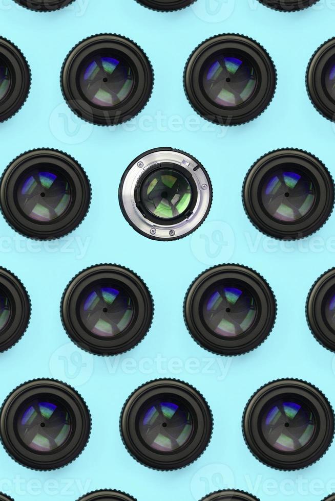 A few camera lenses with a closed aperture lie on texture background of fashion pastel blue color paper photo