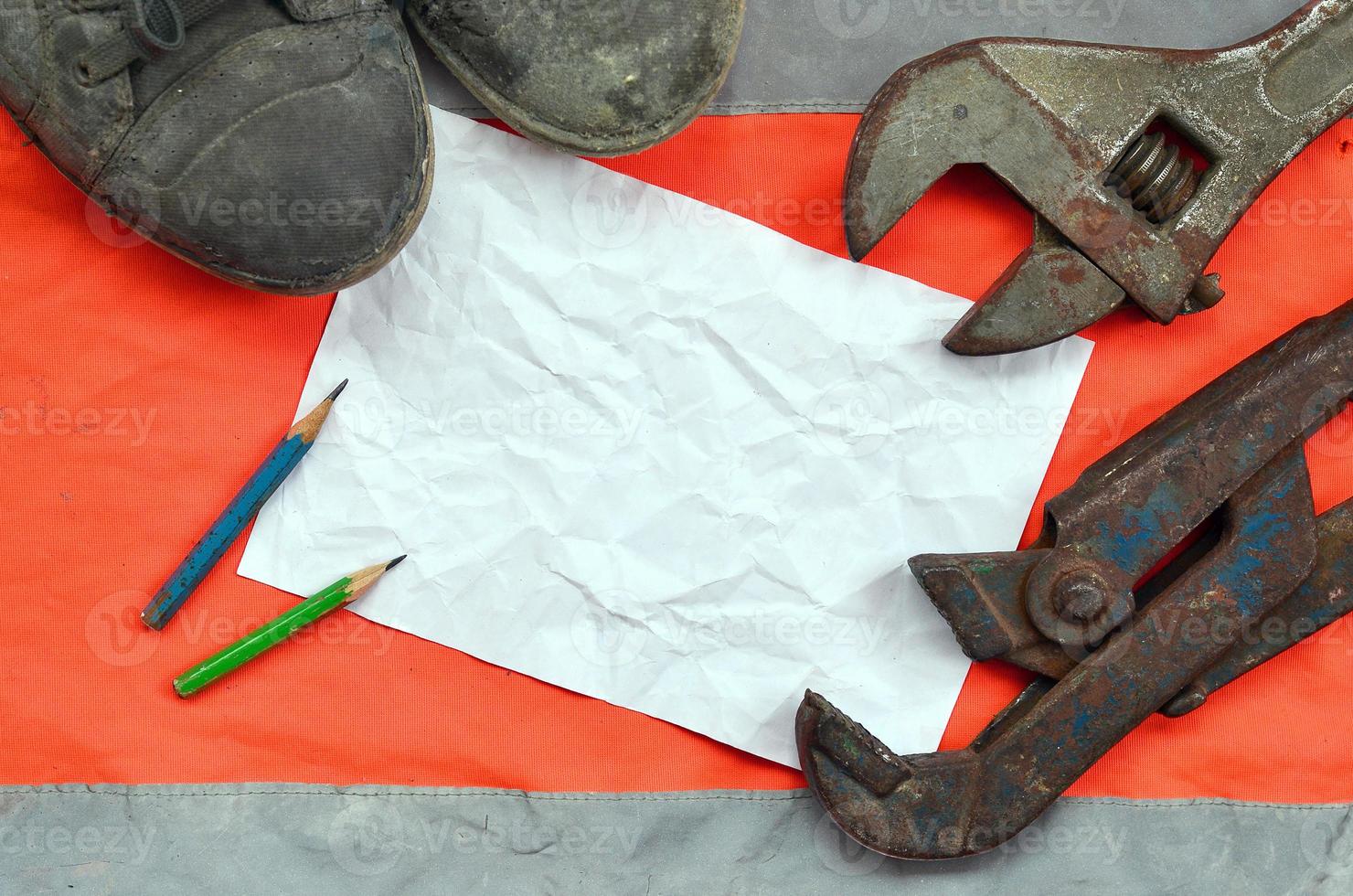 Adjustable wrenches with old boots and a sheet of paper with two pencils photo
