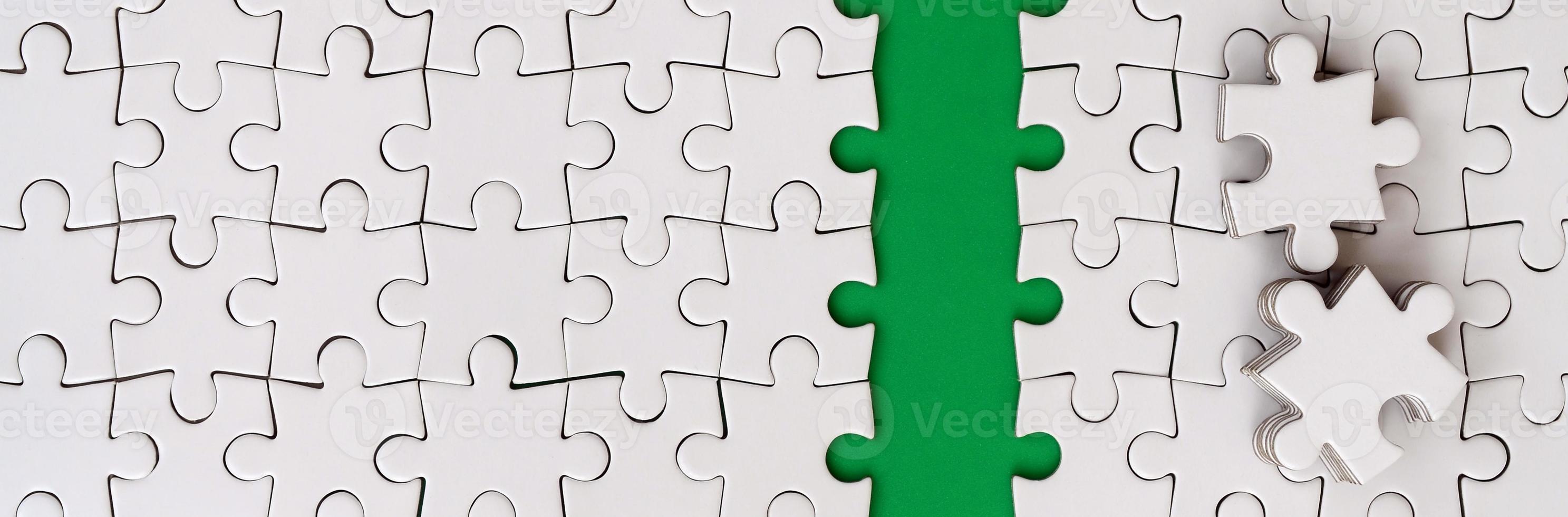 The green path is laid on the platform of a white folded jigsaw puzzle. The missing elements of the puzzle are stacked nearby. Texture image with space for text photo