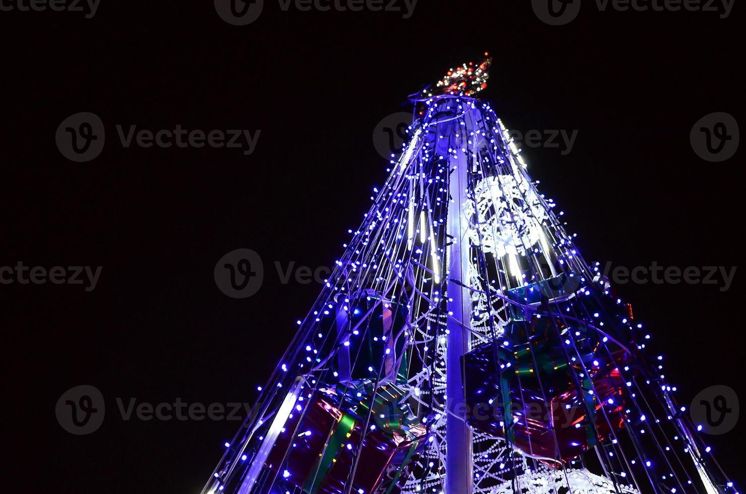 Fragment of the New Year tree. A lot of round lights of blue color are located on a conical frame photo