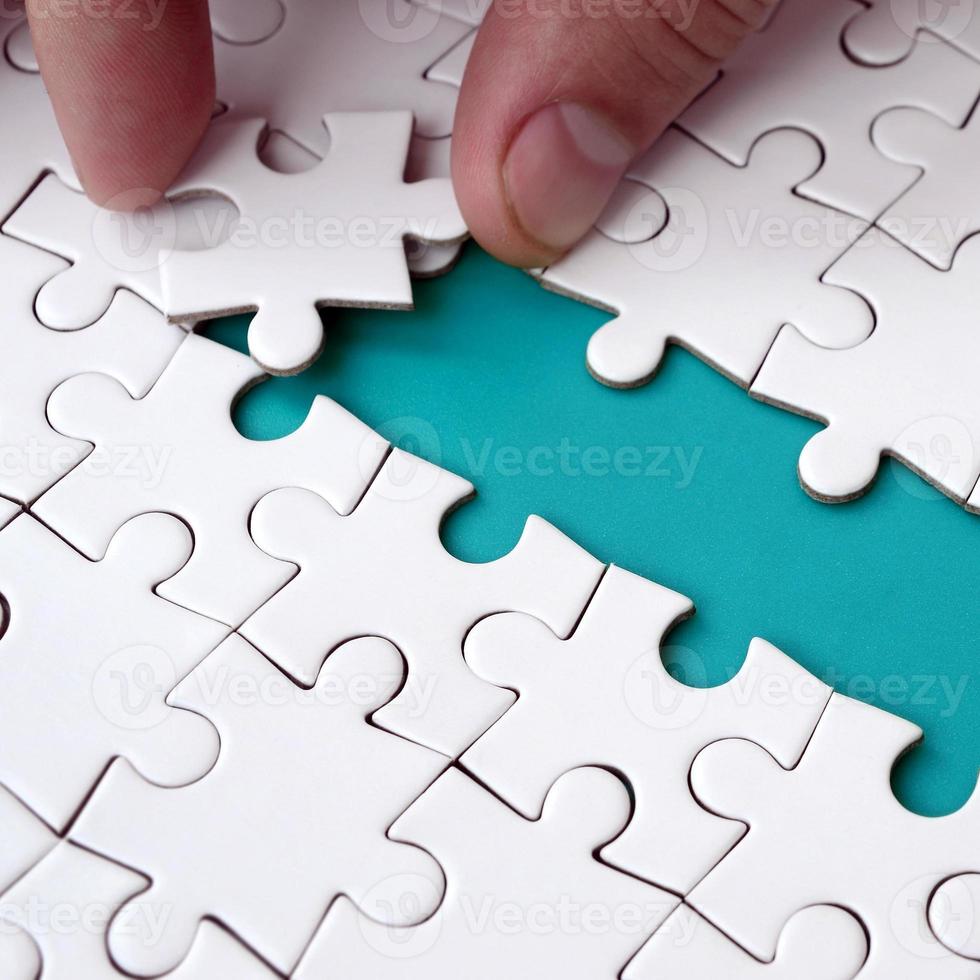 The human hand paves the way to the surface of the jigsaw puzzle, forming a blue space. The concept of overcoming the difficulties on the way to success photo