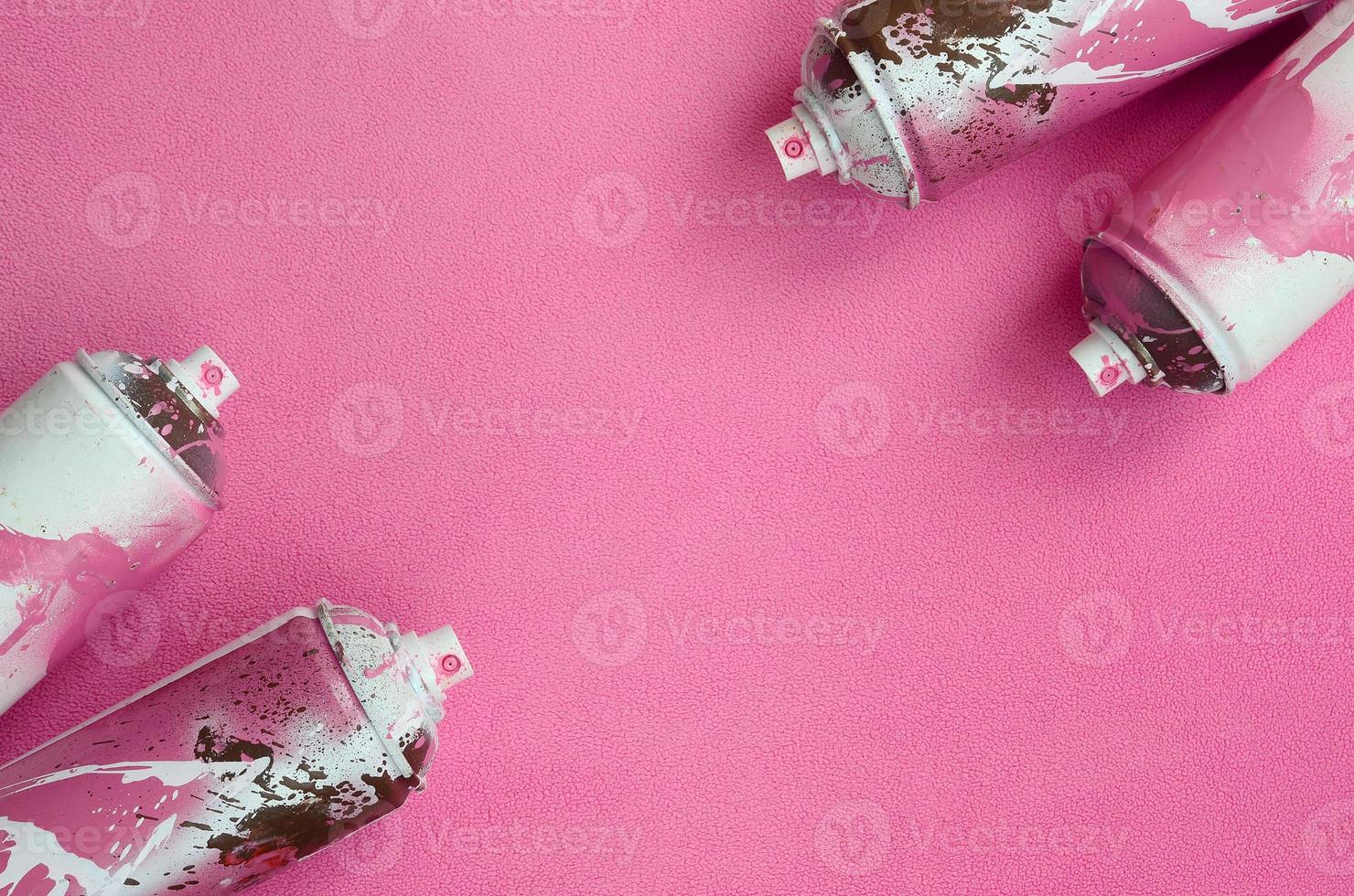 Some used pink aerosol spray cans with paint drips lies on a blanket of soft and furry light pink fleece fabric. Classic female design color. Graffiti hooliganism concept photo