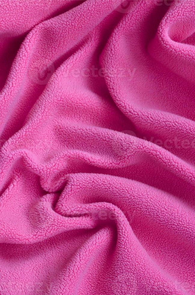 The blanket of furry pink fleece fabric. A background of light pink soft plush fleece material with a lot of relief folds photo