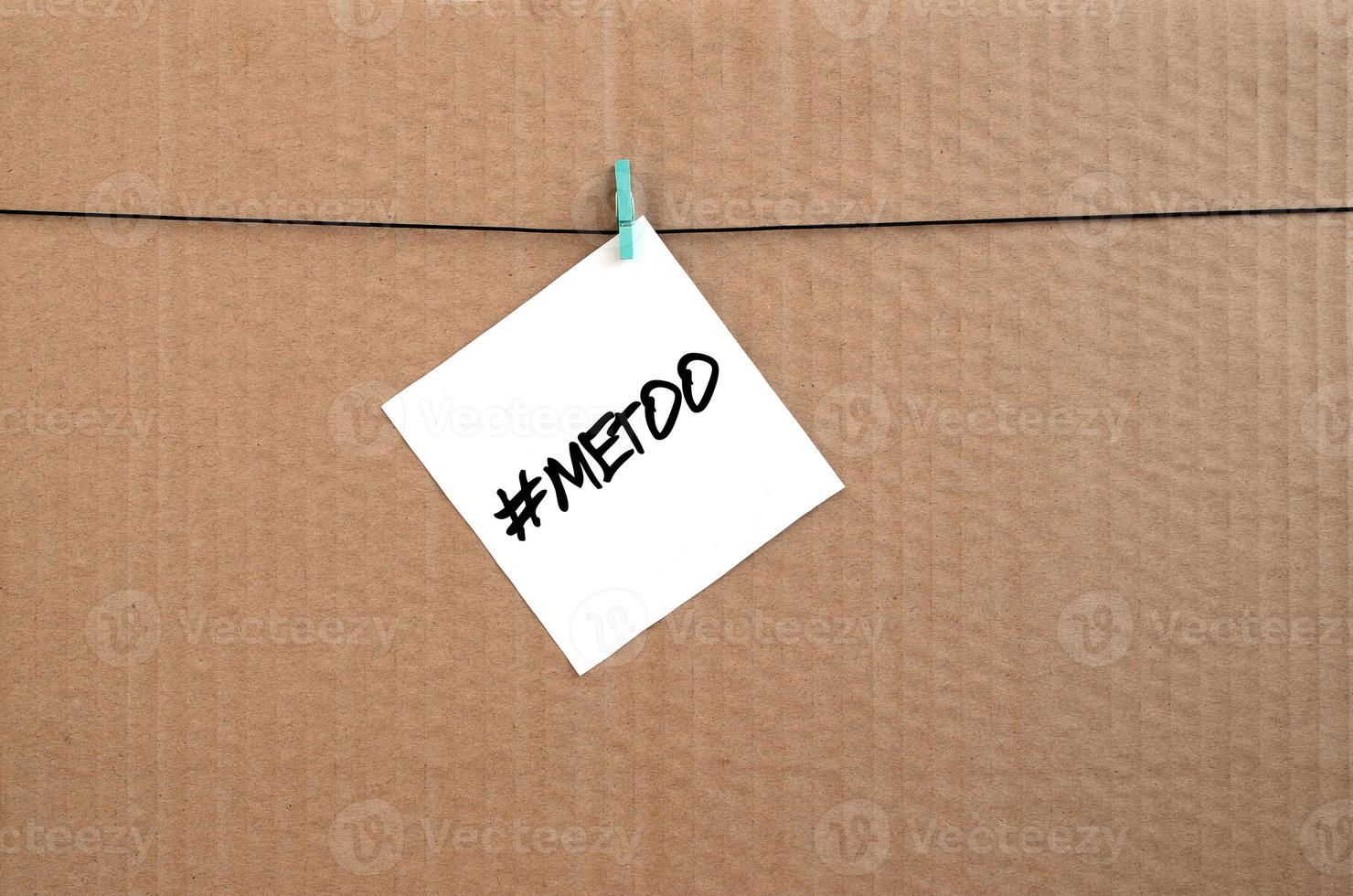 MeToo hashtag. Note is written on a white sticker that hangs with a clothespin on a rope on a background of brown cardboard photo