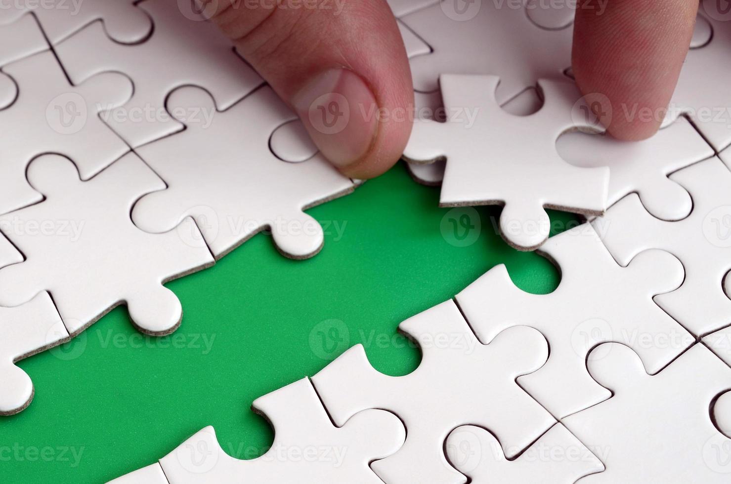 The human hand paves the way to the surface of the jigsaw puzzle, forming a green space. The concept of overcoming the difficulties on the way to success photo