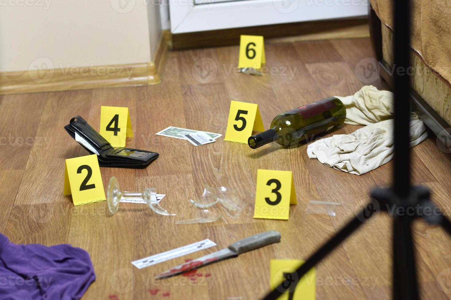 Crime scene investigation - numbering of evidences after the murder in the apartment. Broken glass of wine, knife with clothes, wallet and bottle as evidence photo