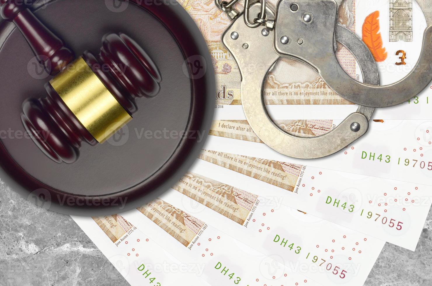10 British pounds bills and judge hammer with police handcuffs on court desk. Concept of judicial trial or bribery. Tax avoidance photo