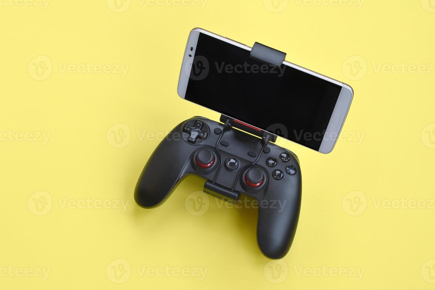 Modern black gamepad for smartphone on yellow background. Mobile video gaming device photo
