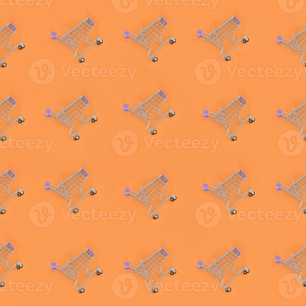 Shopping addiction, shopping lover or shopaholic concept. Many small empty shopping carts perform a pattern on a pastel colored paper background. Flat lay composition, top view photo