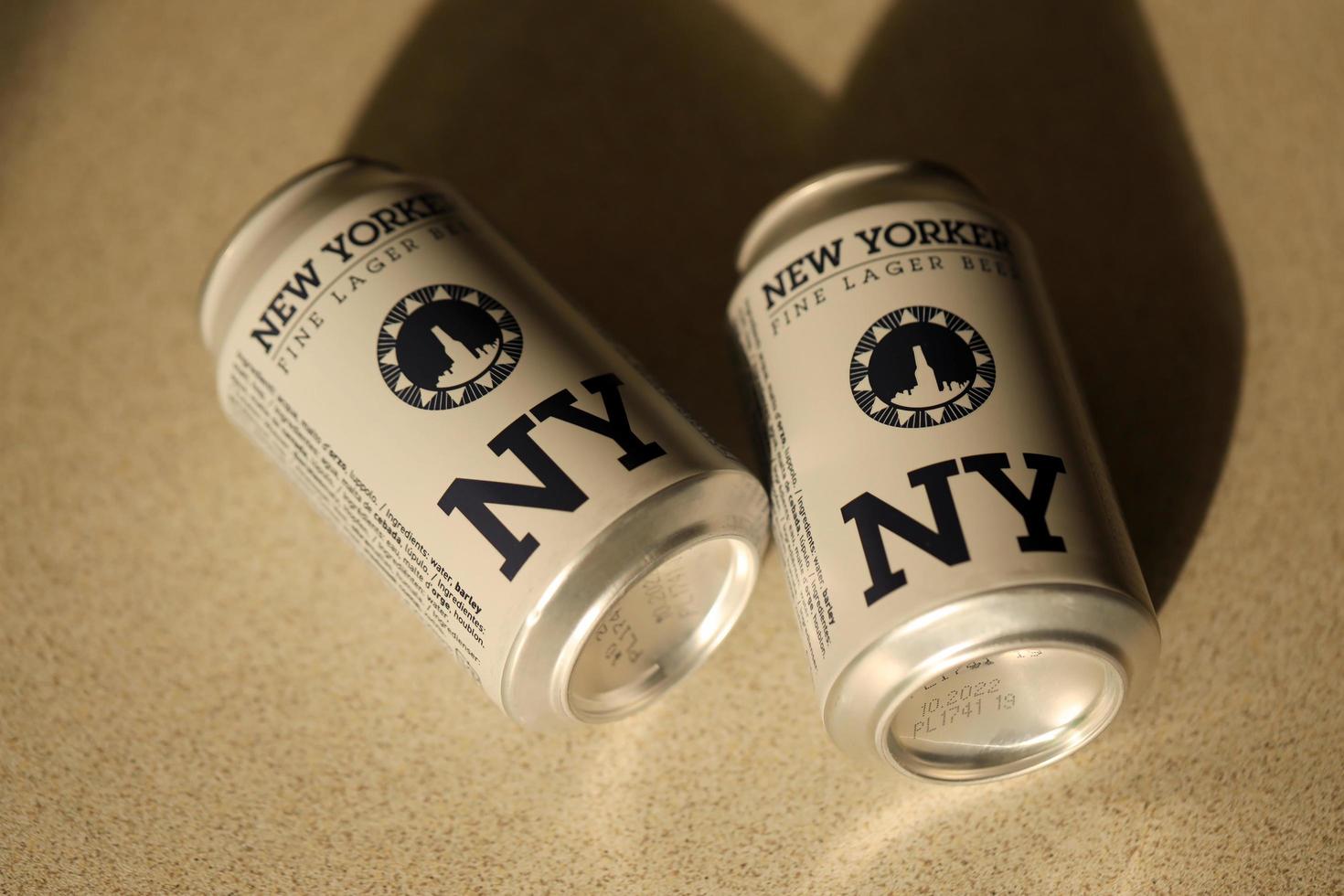 TERNOPIL, UKRAINE - JULY 18, 2022 Two cans of New Yorker fine lager beer with original logo and design on brown retro background photo