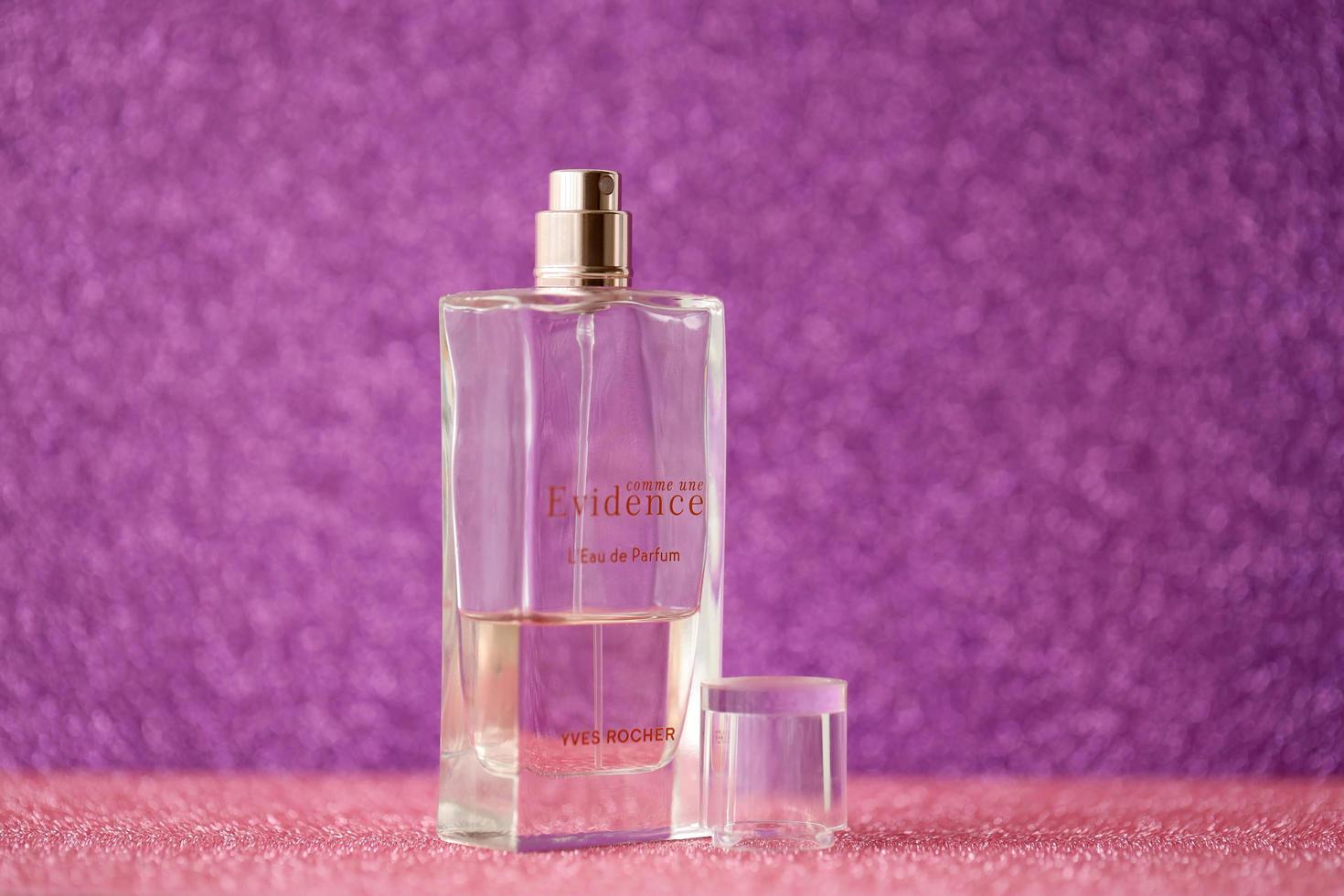 TERNOPIL, UKRAINE - SEPTEMBER 2, 2022 Yves Rocher Comme Une Evidence perfume bottle on shiny glitter background in purple colors photo