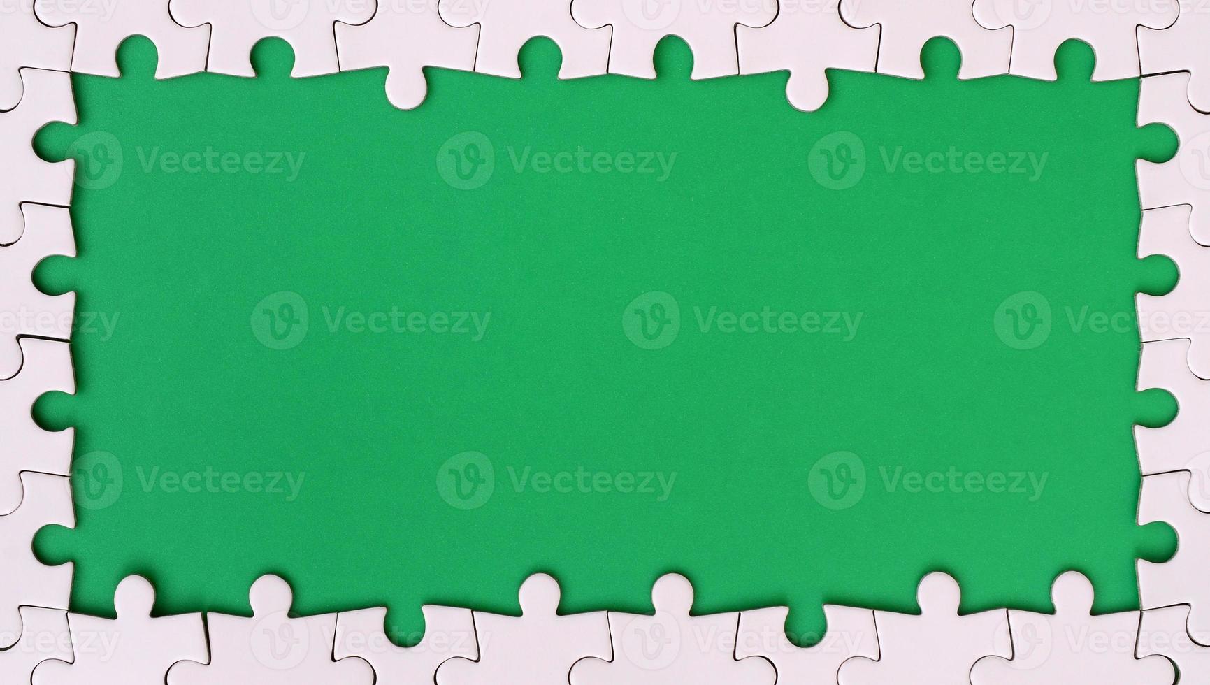 Framing in the form of a rectangle, made of a white jigsaw puzzle around the green space photo