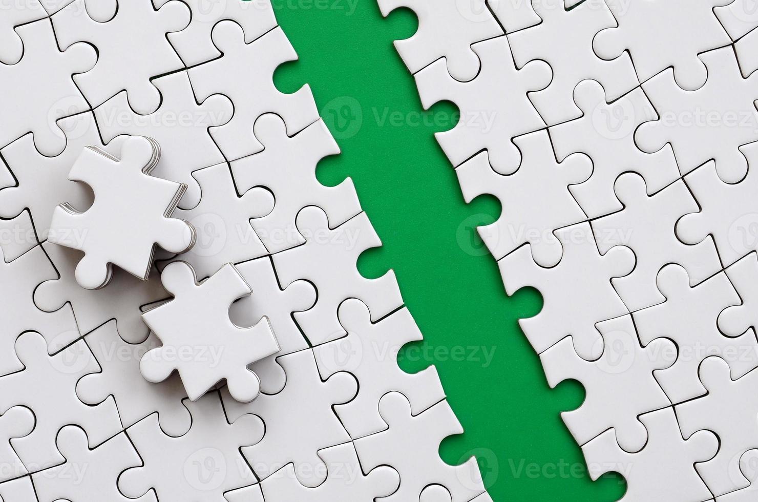 The green path is laid on the platform of a white folded jigsaw puzzle. The missing elements of the puzzle are stacked nearby. Texture image with space for text photo