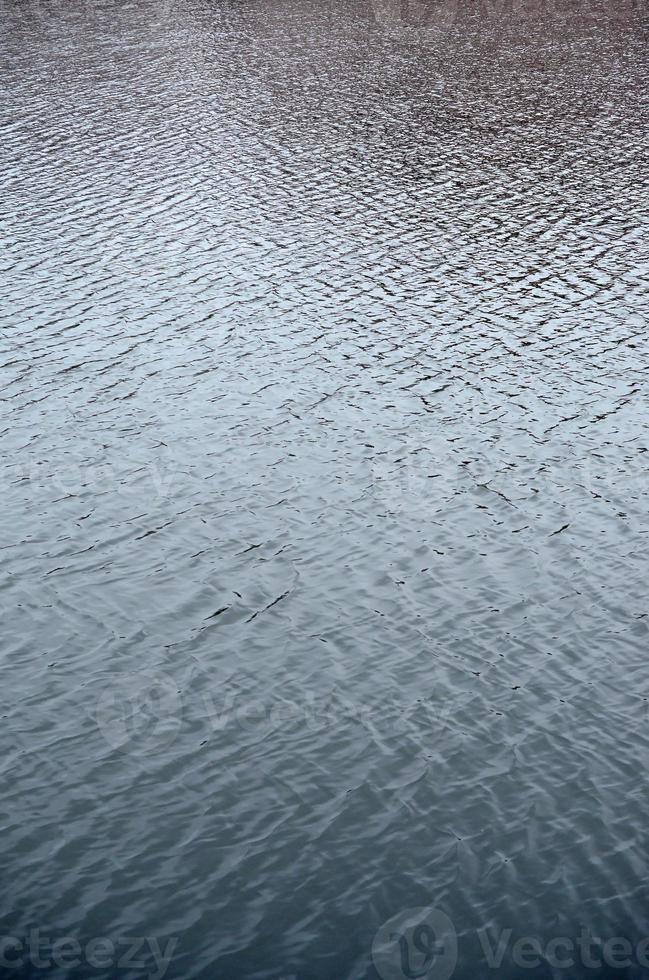 The texture of the water in the river under the influence of wind. A lot of shallow waves on the water surface photo