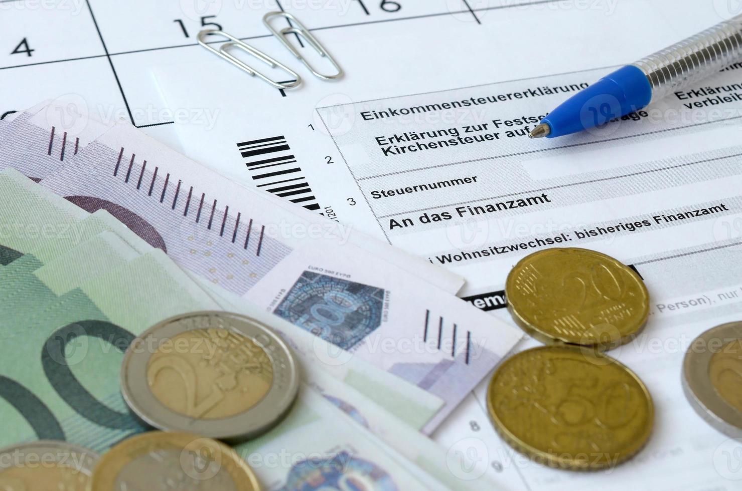 el formulario de impuestos alemán con bolígrafo y billetes de dinero europeos se encuentra en el calendario de la oficina. contribuyentes en alemania que usan la moneda euro para pagar impuestos foto