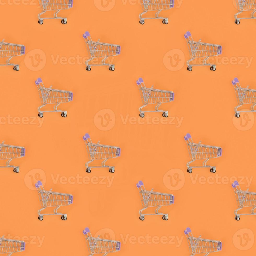 Shopping addiction, shopping lover or shopaholic concept. Many small empty shopping carts perform a pattern on a pastel colored paper background. Flat lay composition, top view photo