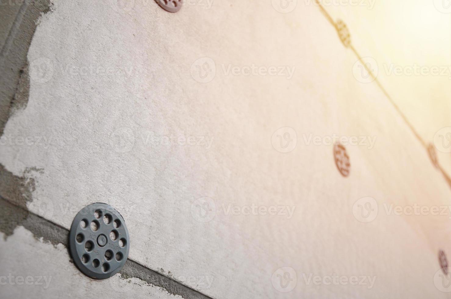 la textura de la pared, recubierta con placas de poliestireno expandido gris, que se refuerzan con tacos de plástico tipo paraguas. etapa de aislamiento de la pared foto