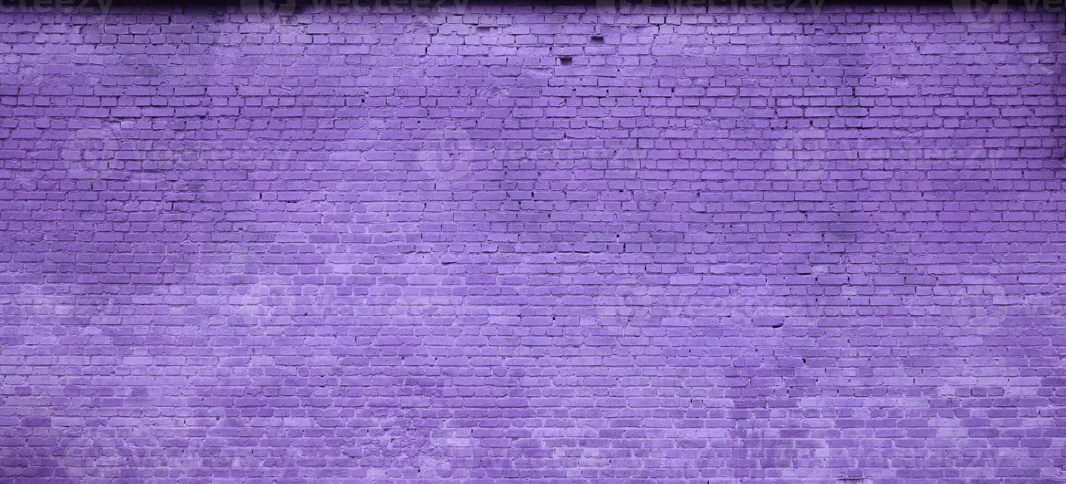 The texture of the brick wall of many rows of bricks painted in violet color photo