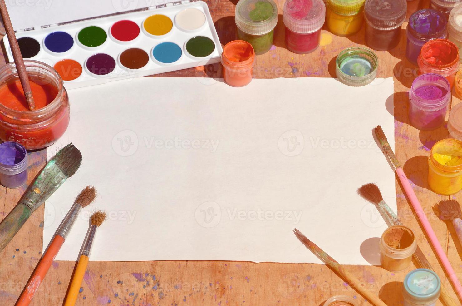Still life with blank paper, brushes and jars of watercolor and gouache paint photo