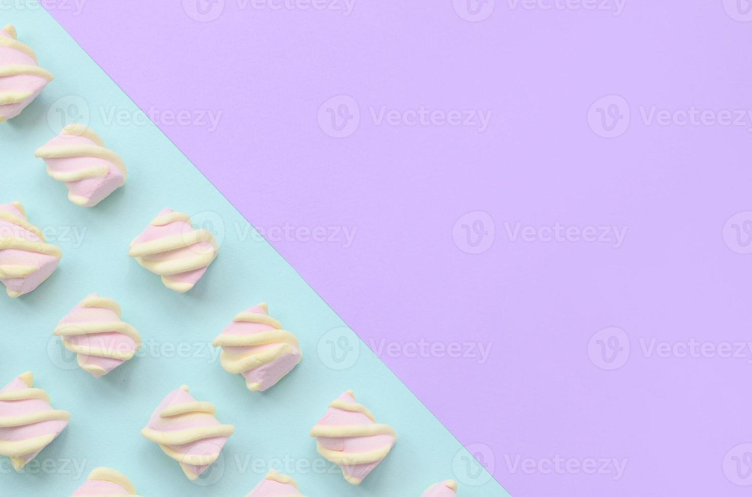 Colorful marshmallow laid out on violet and blue paper background. pastel creative textured pattern. minimal photo