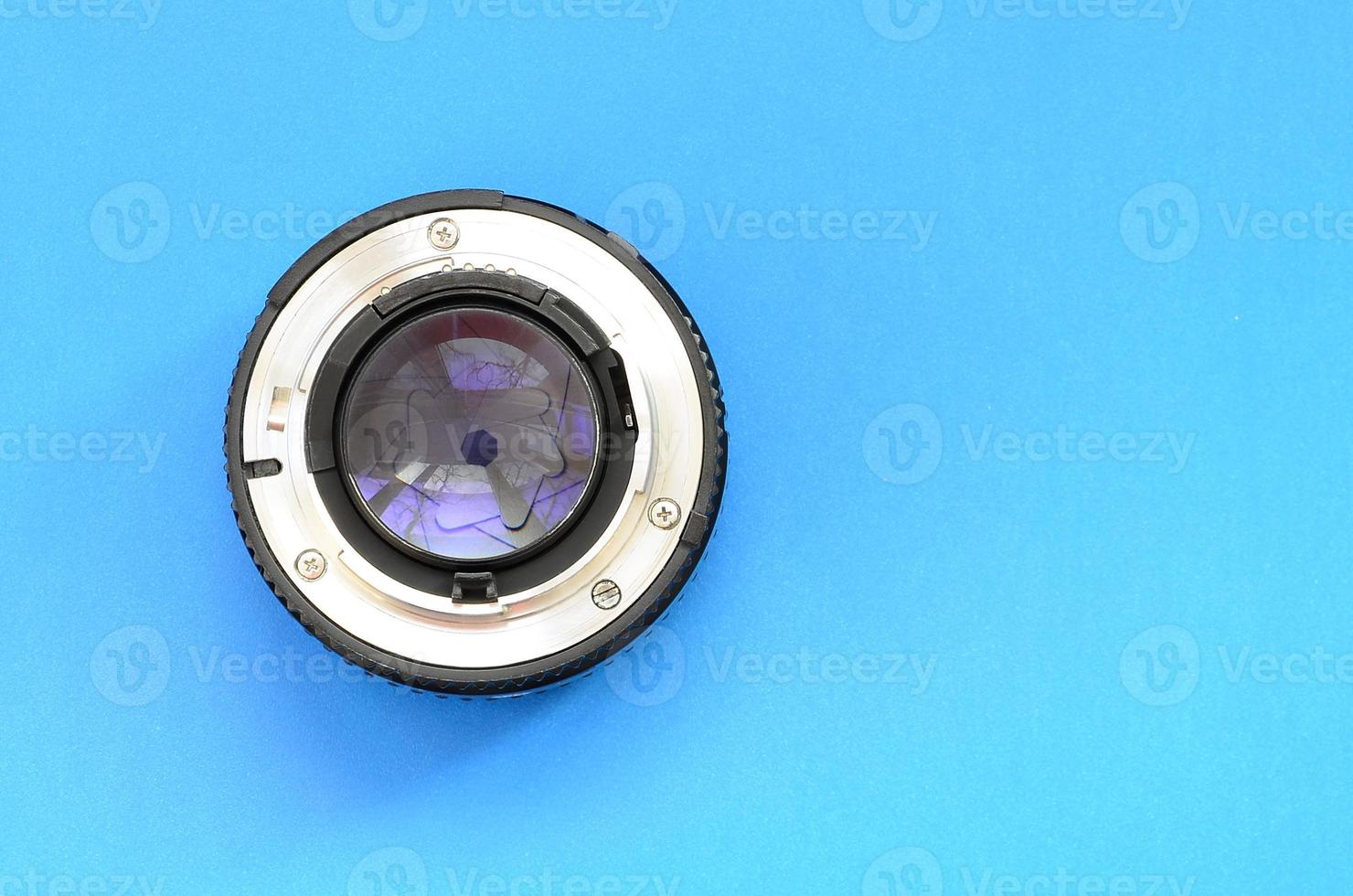 One photographic lense lie on a bright blue background. Space for text photo