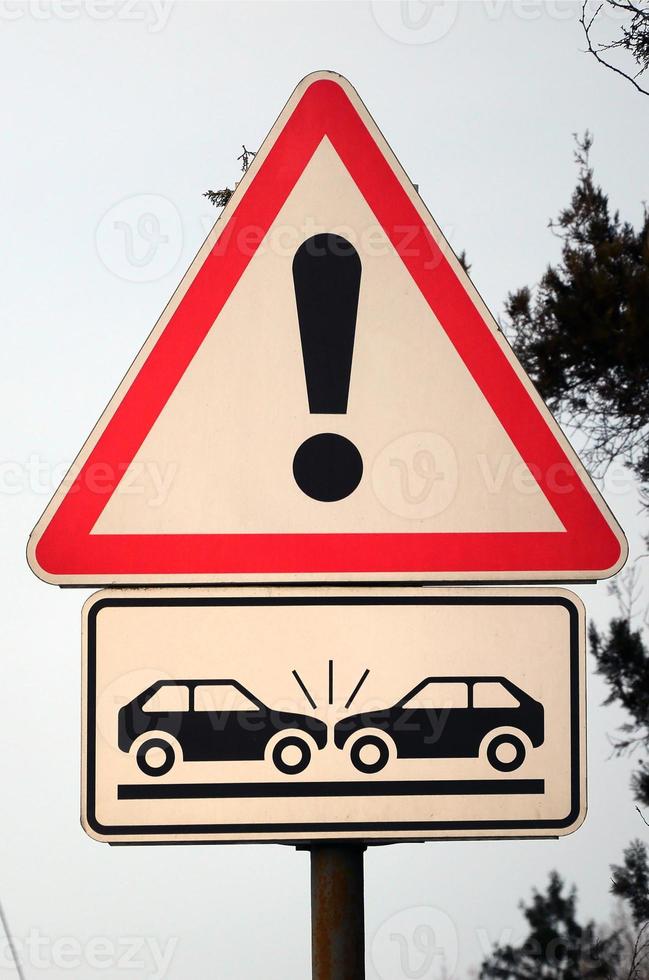 High risk of collision. A road sign with an exclamation point and two cars that crashed into each other photo