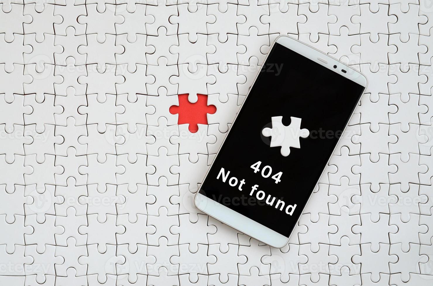 A modern big smartphone with a touch screen lies on a white jigsaw puzzle in an assembled state with inscription. 404 Not found photo