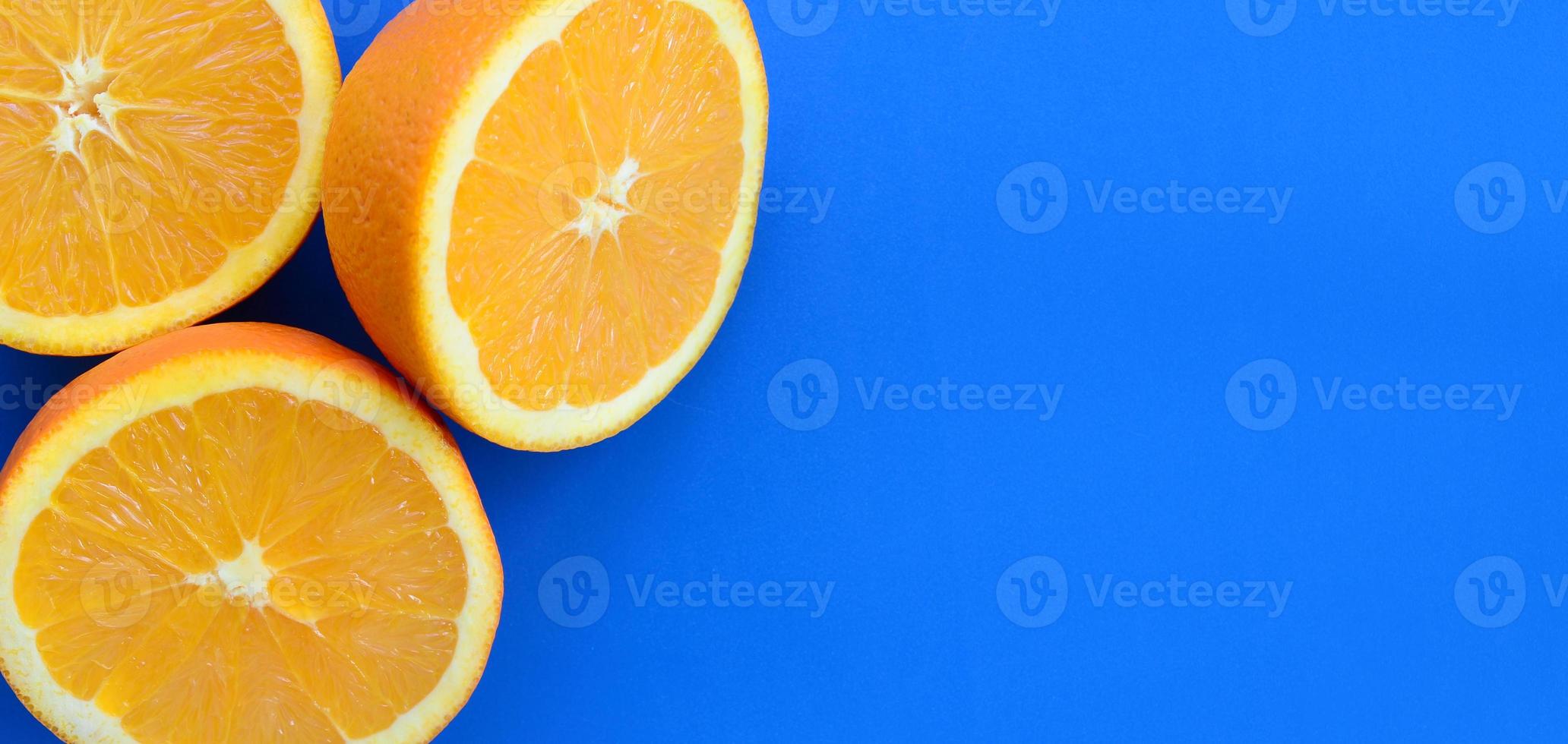 Top view of a several orange fruit slices on bright background in blue color. A saturated citrus texture image photo