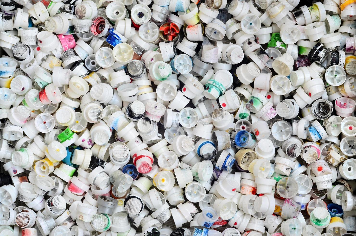 A pattern of many used and soiled nozzles from spray cans with aerosol paint. Background texture of the street art of drawing graffiti on the walls photo