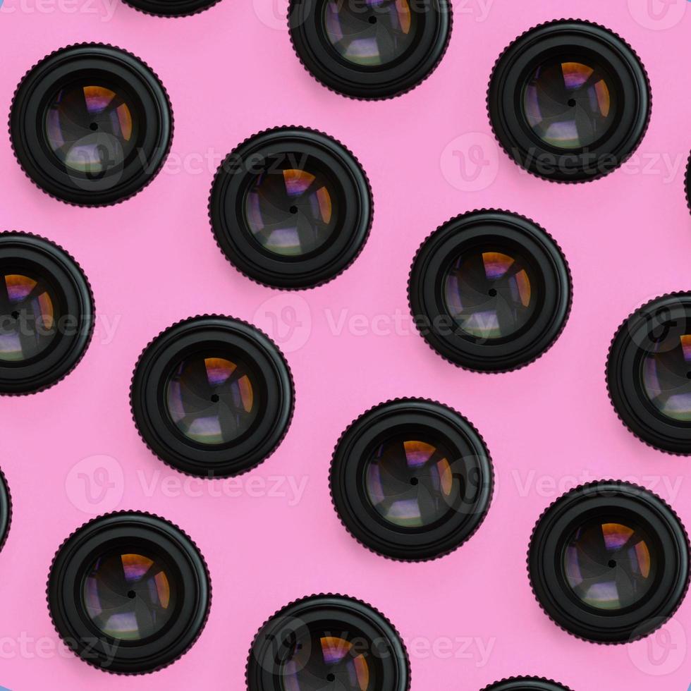 A few camera lenses with a closed aperture lie on texture background of fashion pastel pink color paper in minimal concept. Abstract trendy pattern photo