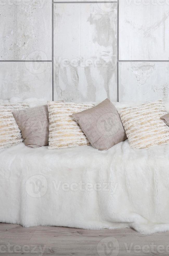 Many pillows lie on the couch, which is covered with a large plush veil