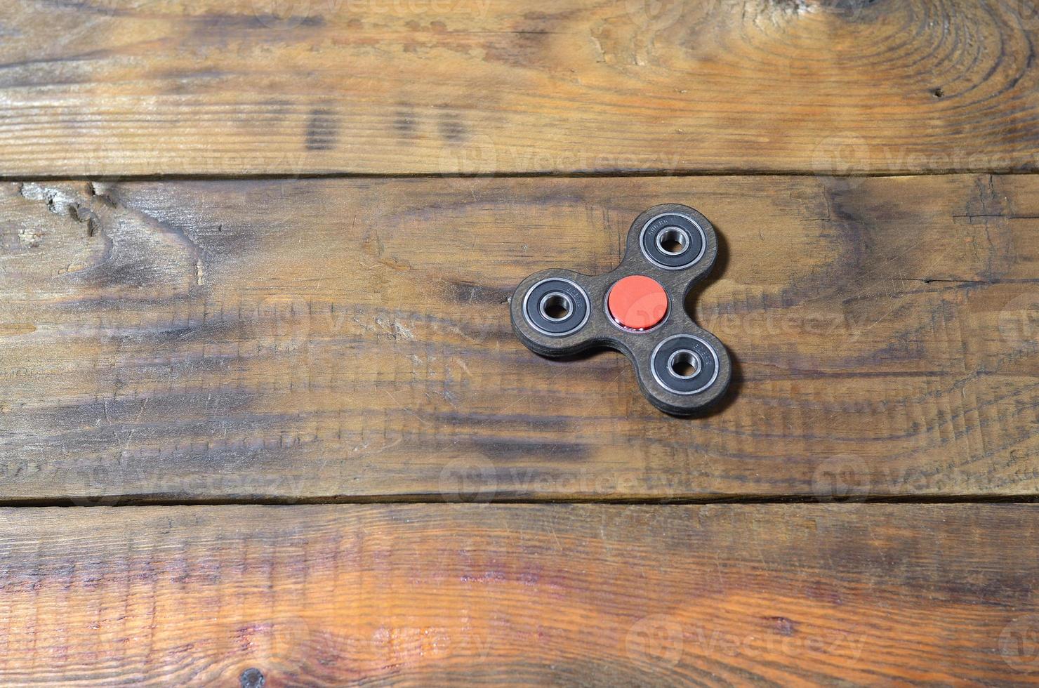 A rare handmade wooden fidget spinner lies on a brown wooden background surface. Trendy stress relieving toy photo