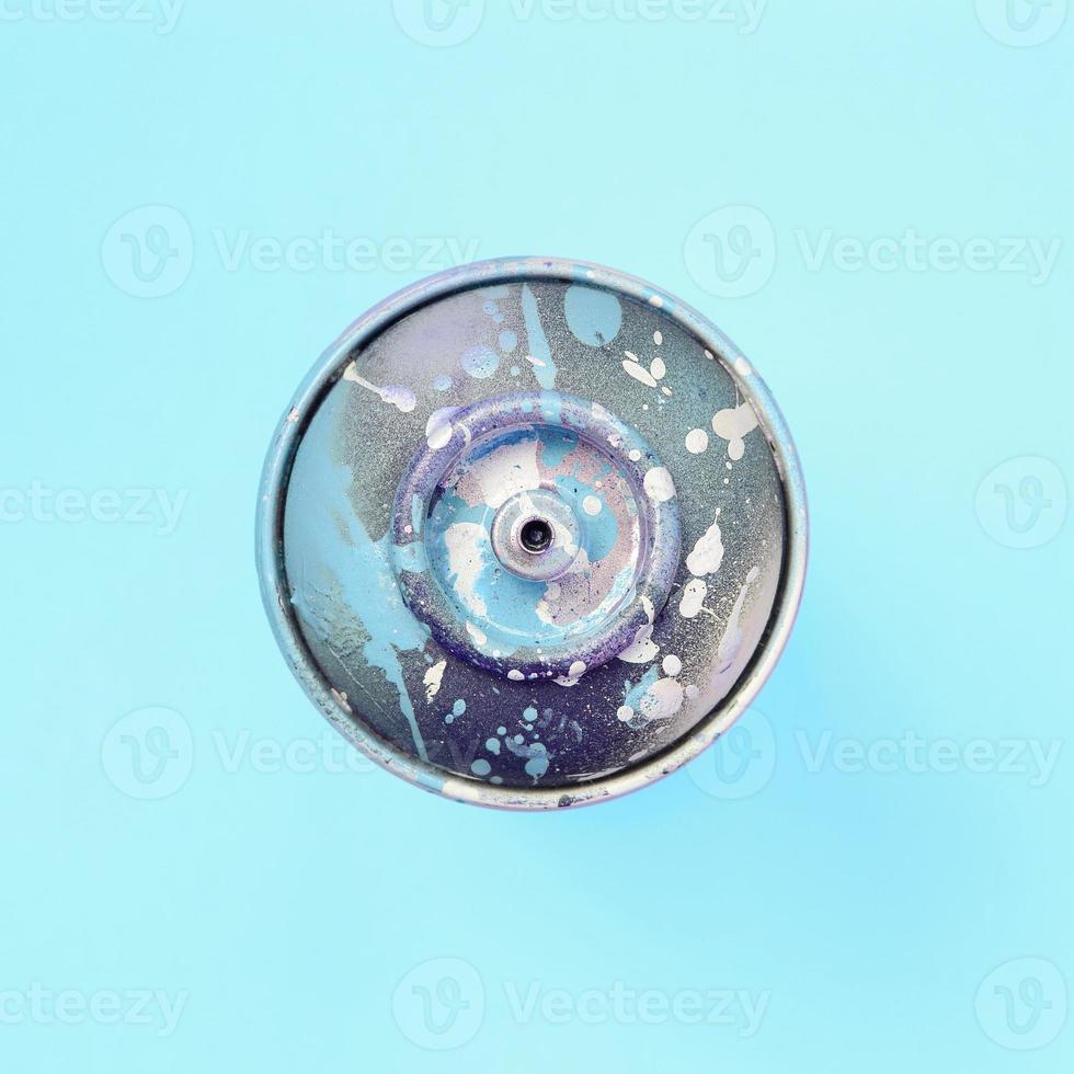 Used spray can with blue paint drips lie on texture background of fashion pastel blue color paper photo