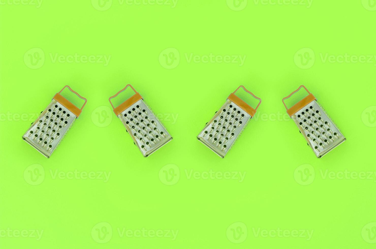 Small stainless steel graters lies on a pastel colored paper. Kitchen accessories. Tools for cooking. Flat lay top view photo