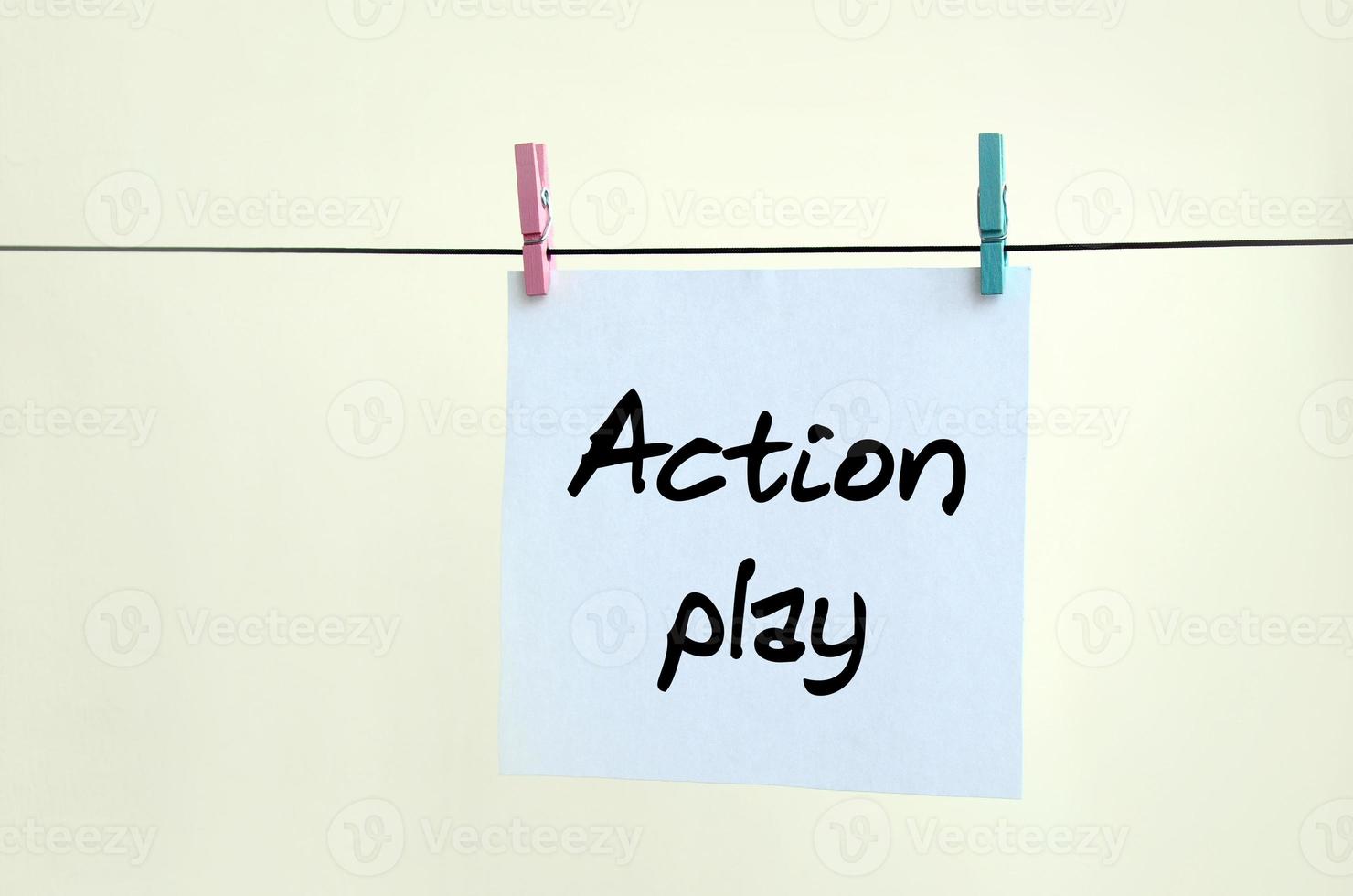 Action play. Note is written on a white sticker that hangs with a clothespin on a rope on a background of beige wall photo