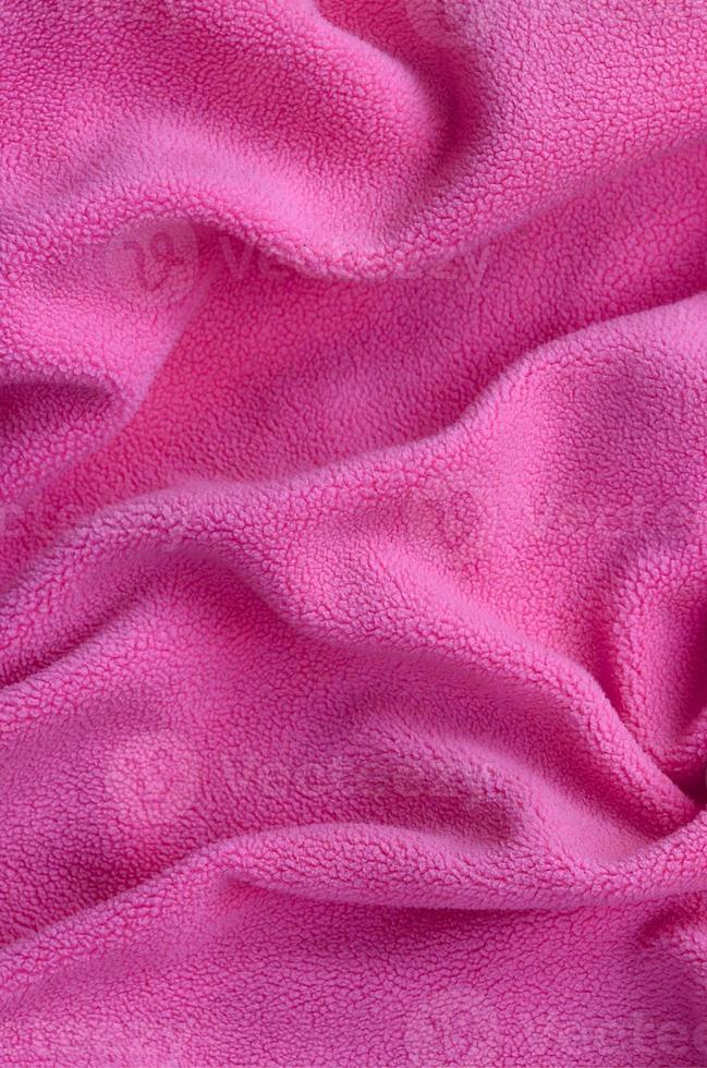 The blanket of furry pink fleece fabric. A background of light pink soft plush fleece material with a lot of relief folds photo