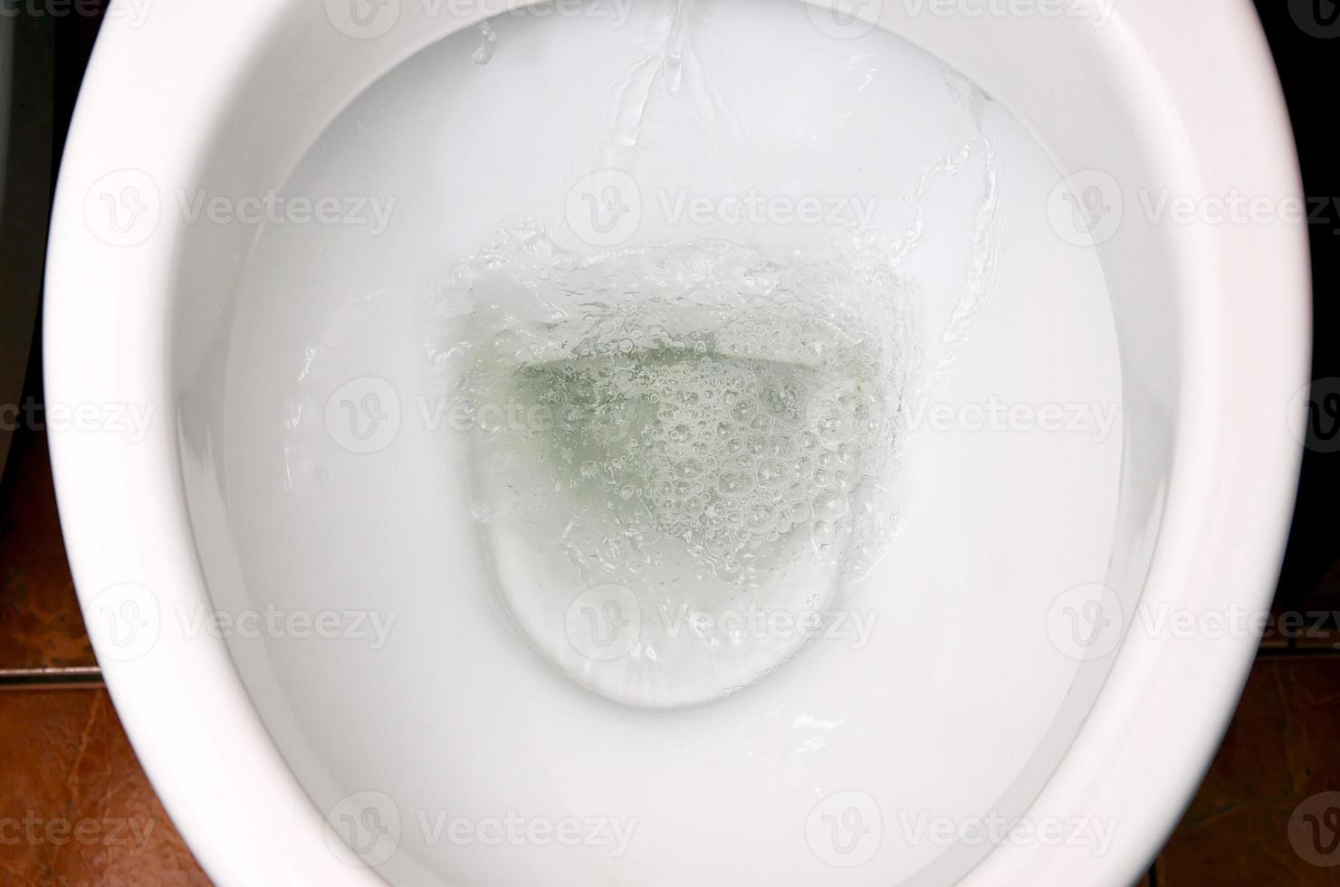 A photo of a white ceramic toilet bowl in the process of washing it off. Ceramic sanitary ware for correcting the need with an automatic flushing device