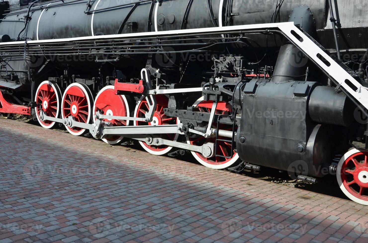 Wheels of the old black steam locomotive of Soviet times. The side of the locomotive with elements of the rotating technology of old trains photo