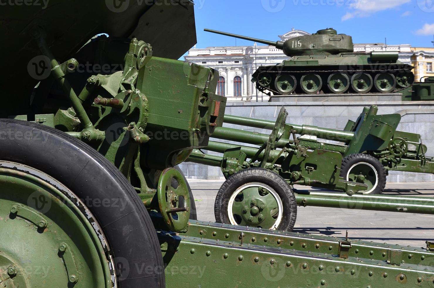 Photo of three guns of the Soviet Union of the Second World War against the background of the green tank T-34