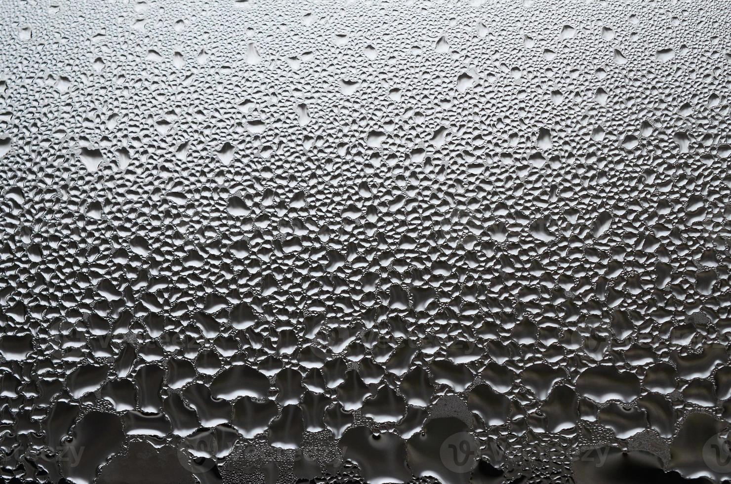 A photo of the glass surface of the window, covered with a multitude of droplets of various sizes. Background texture of a dense layer of condensate on glass
