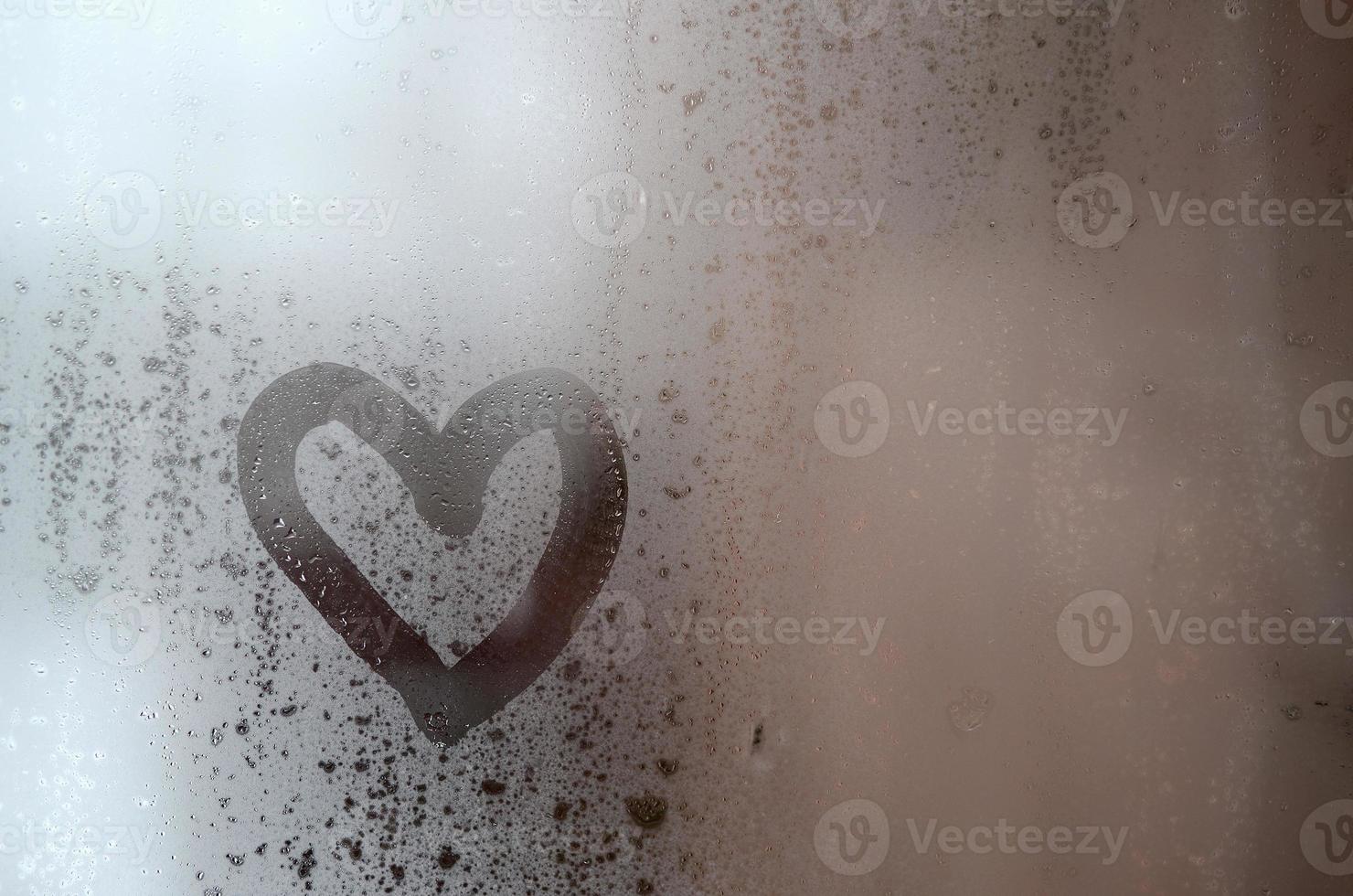 The heart is painted on the misted glass in winter photo